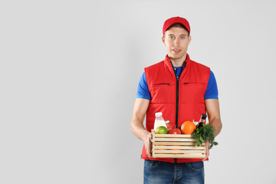 Photo of Courier with fresh products on light background, space for text. Food delivery service