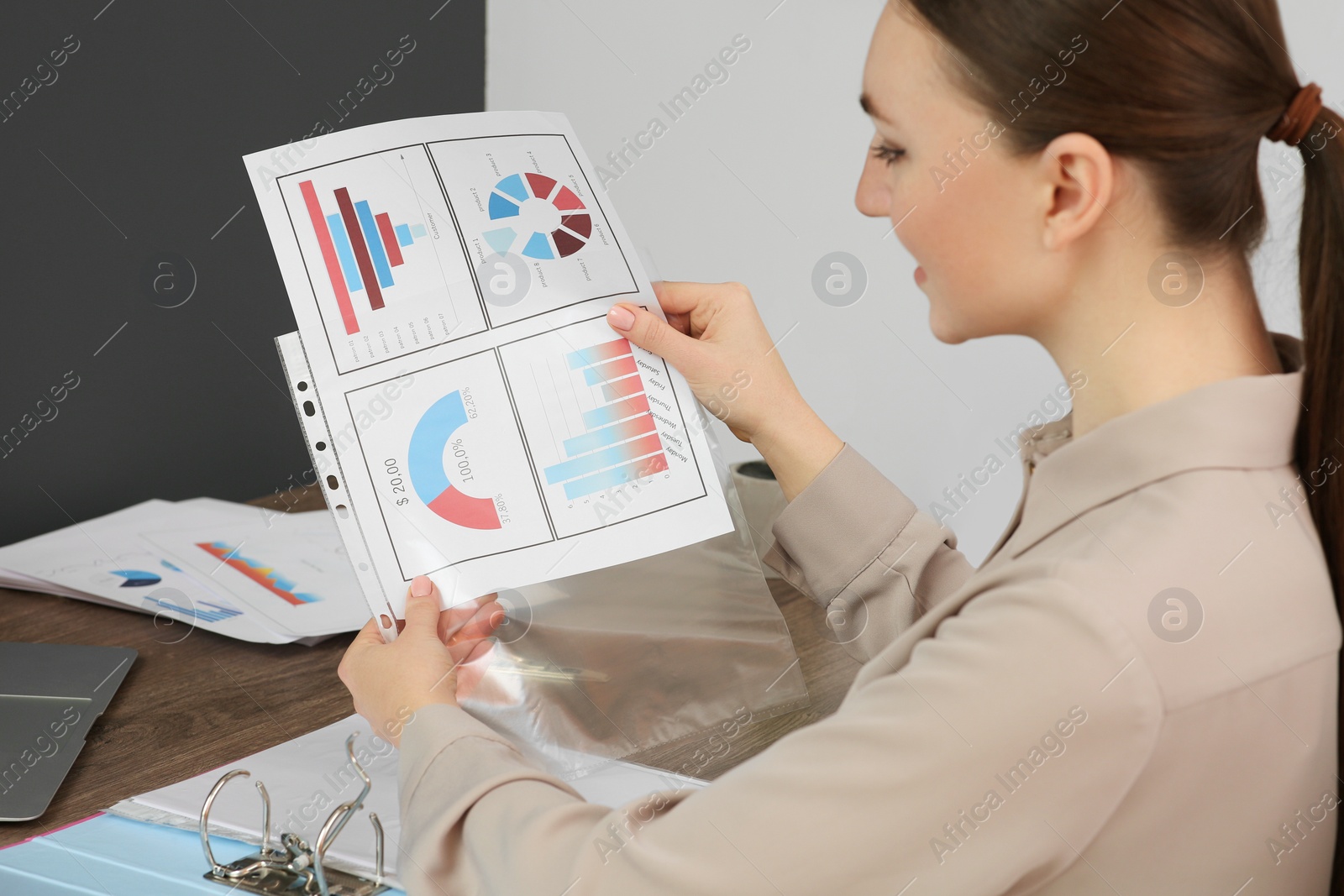 Photo of Businesswoman working with charts at wooden table in office