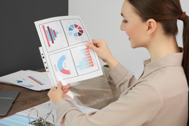 Photo of Businesswoman working with charts at wooden table in office
