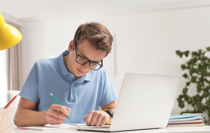 Photo of Teenager boy doing his homework at desk indoors