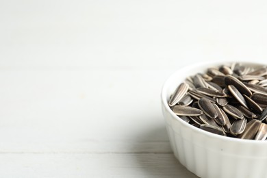 Organic sunflower seeds on white wooden table, closeup. Space for text