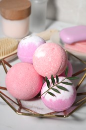 Beautiful aromatic bath bombs and green twig on white table, closeup