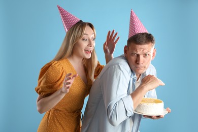 Photo of Greedy man hiding birthday cake from woman on turquoise background