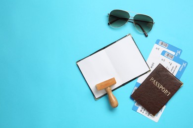 Flat lay composition with passports and visa stamp on light blue background. Space for text