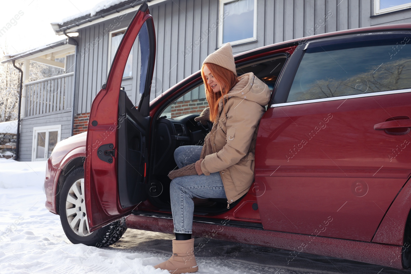 Photo of Beautiful young woman getting out of car. Winter vacation