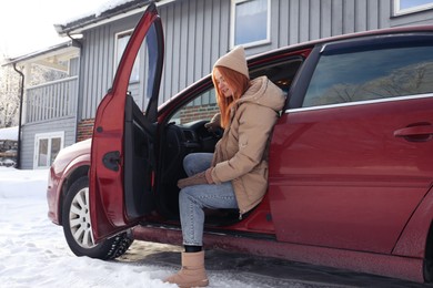 Beautiful young woman getting out of car. Winter vacation