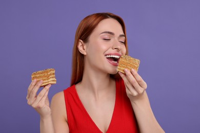 Photo of Young woman eating pieces of tasty cake on purple background