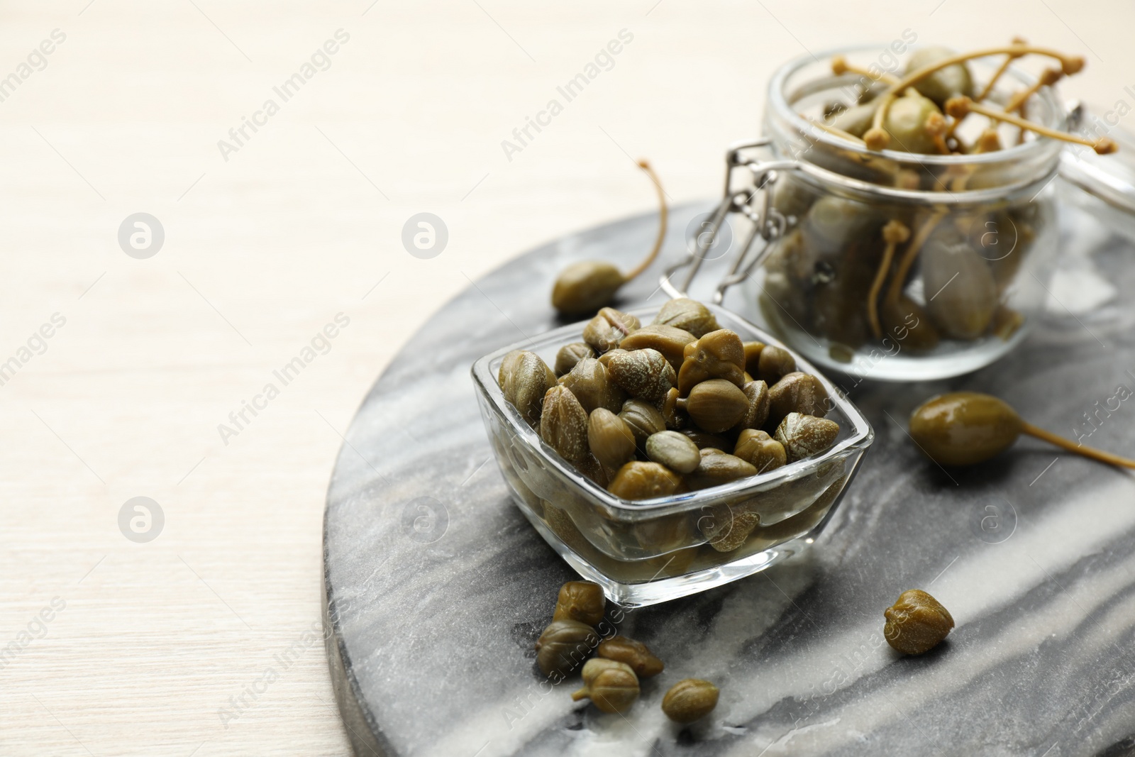 Photo of Delicious pickled capers on white wooden table, space for text