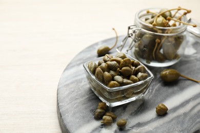 Photo of Delicious pickled capers on white wooden table, space for text