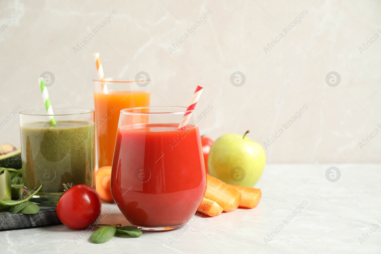 Photo of Delicious vegetable juices and fresh ingredients on light grey table. Space for text