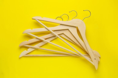 Photo of Empty wooden hangers on yellow background, flat lay