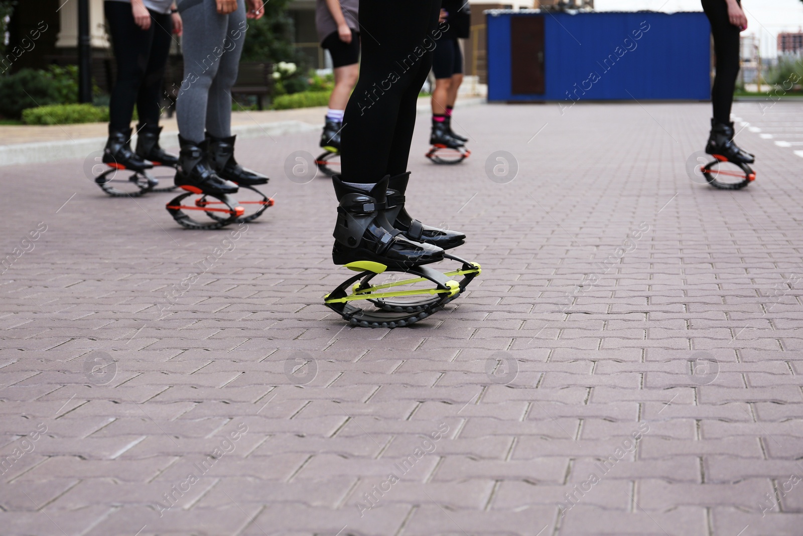 Photo of Group of people doing exercises in kangoo jumping boots outdoors, closeup