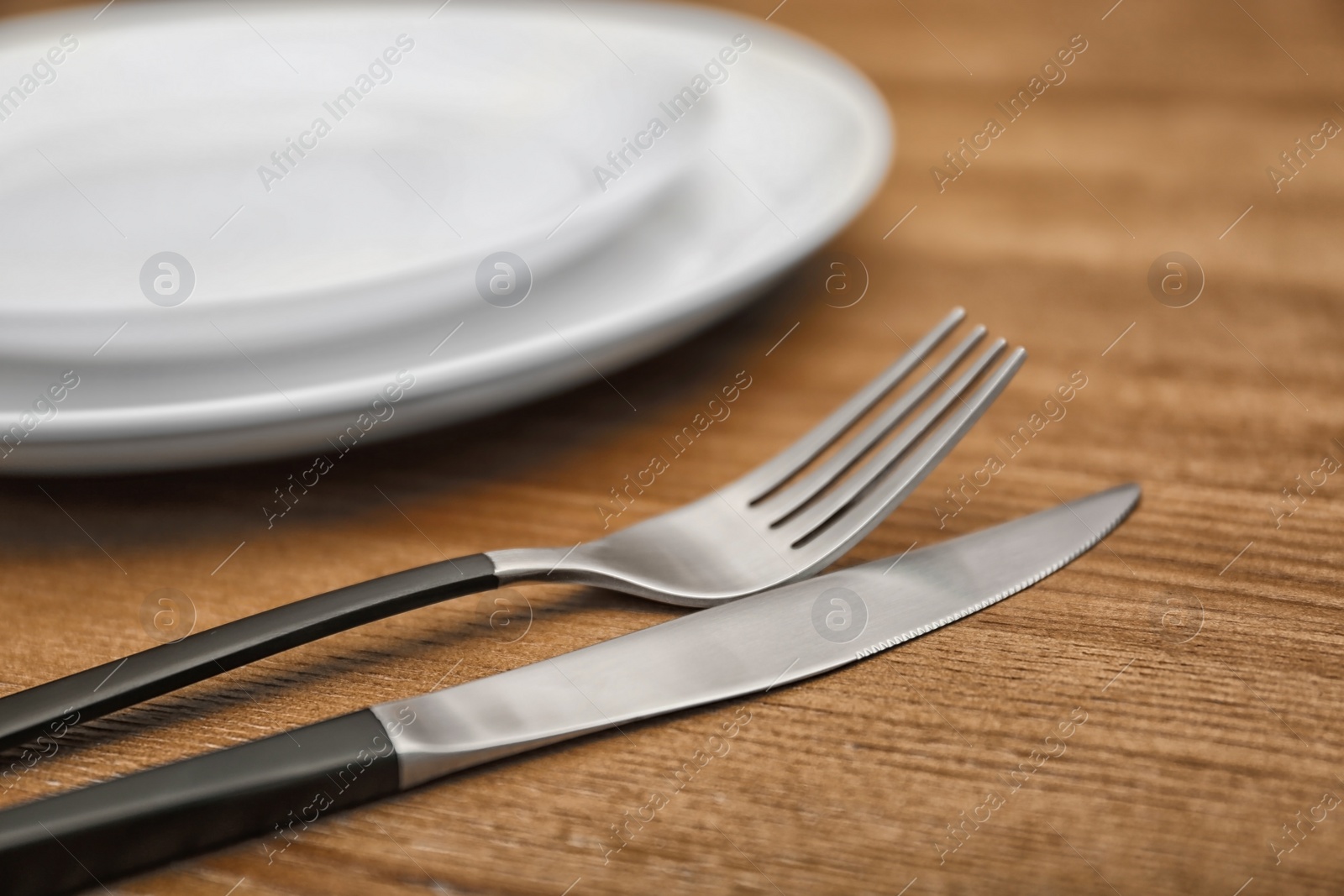 Photo of Empty dishware and cutlery on wooden table, close up view. Table setting