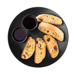 Photo of Black plate with tasty cantucci and glasses of liqueur on white background, top view. Traditional Italian almond biscuits
