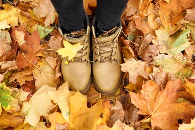 Woman standing on bright autumn leaves, top view