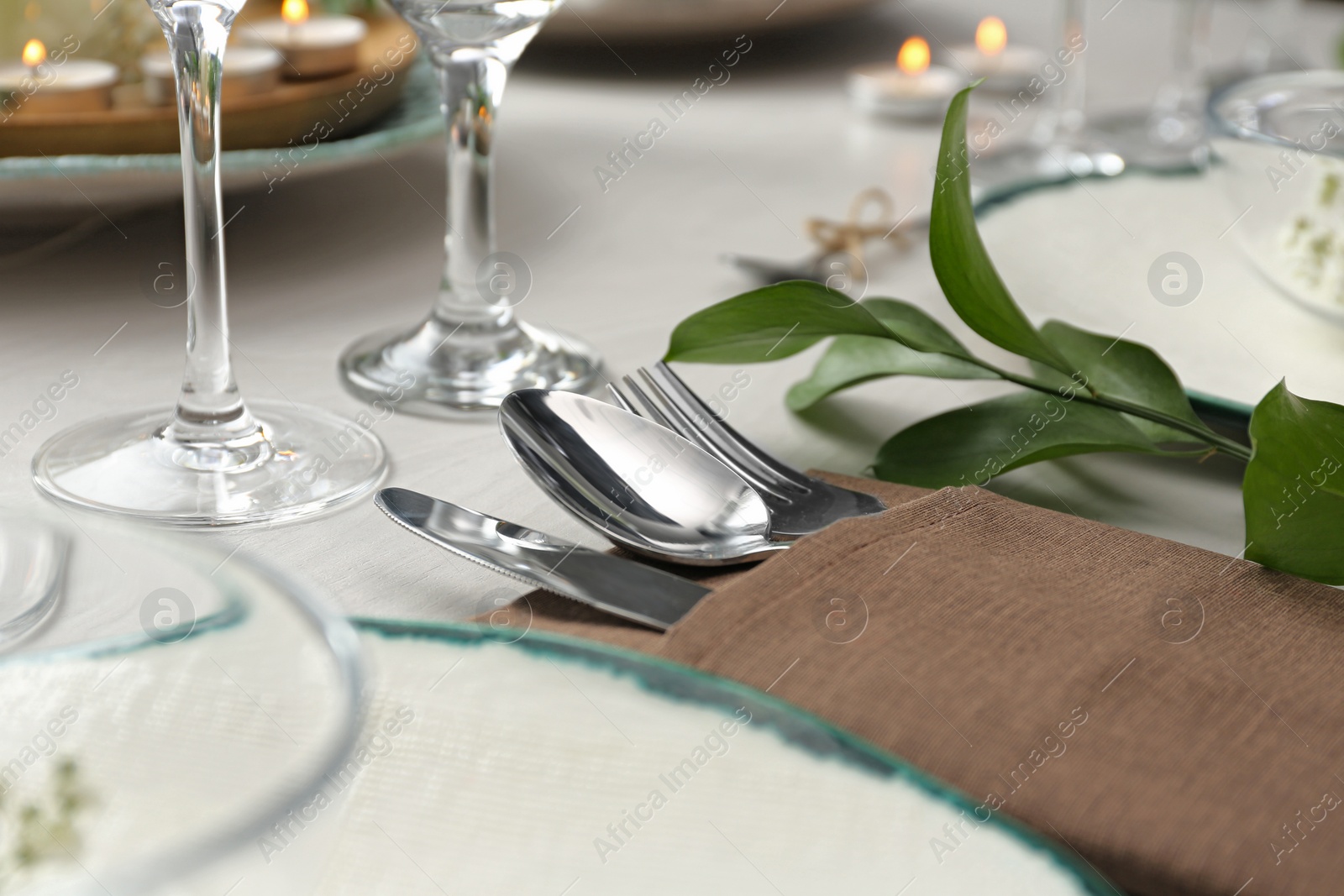 Photo of Elegant cutlery with green plant on table, closeup. Festive setting