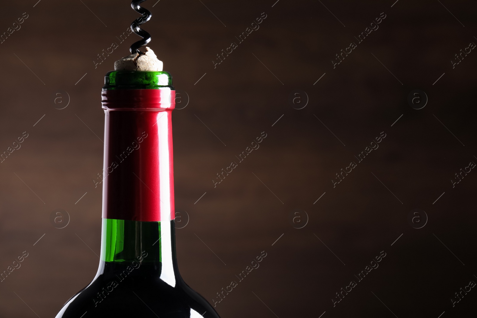 Photo of Opening wine bottle with corkscrew on dark background, closeup. Space for text