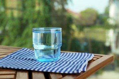 Photo of Glass of pure water on wooden table, space for text