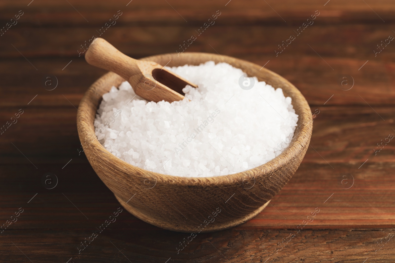 Photo of Bowl with natural sea salt and scoop on wooden table