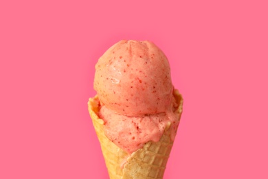 Delicious ice cream in waffle cone on pink background, closeup