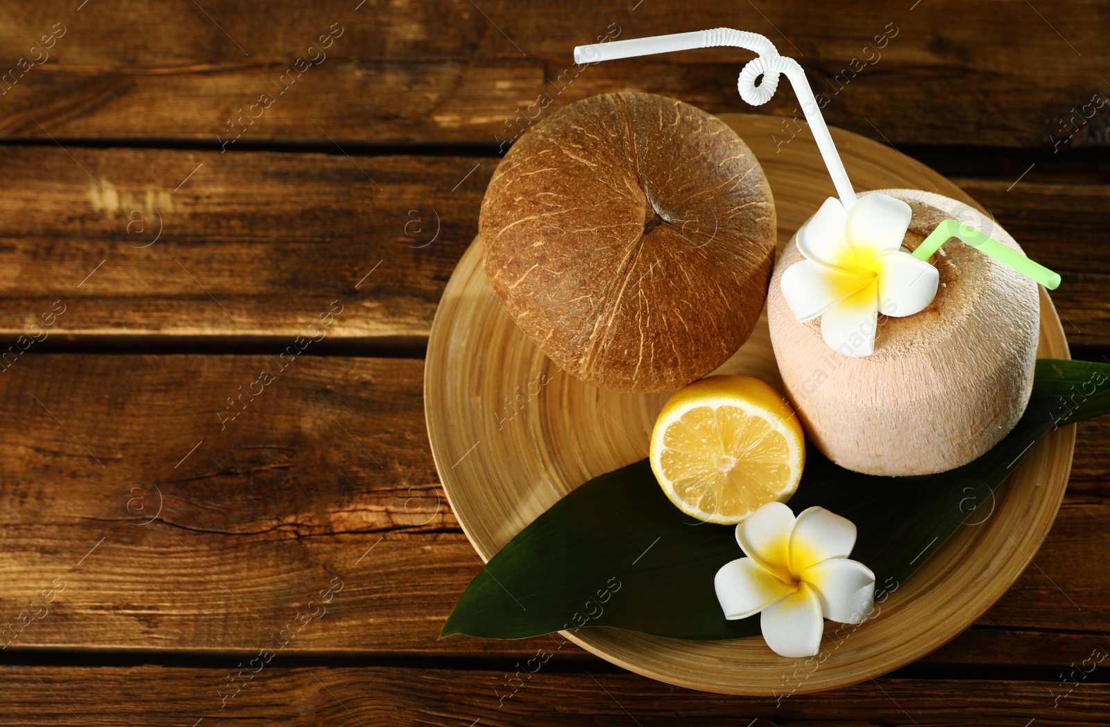 Photo of Plate with coconuts and lemon on wooden table. Space for text