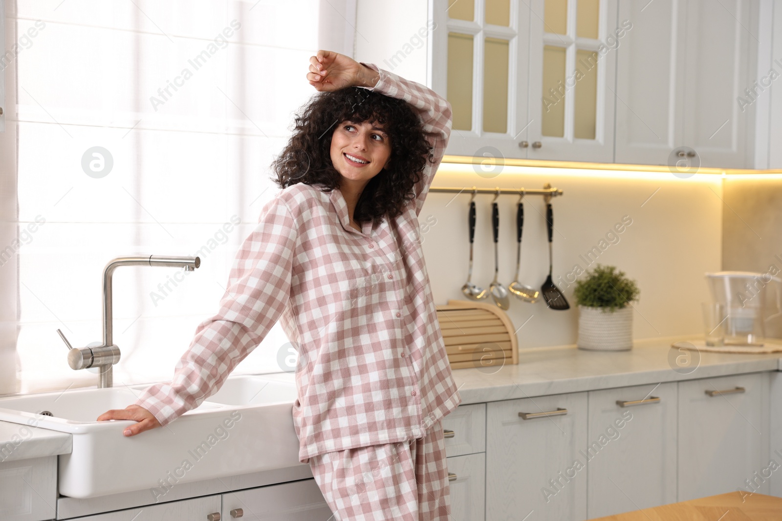 Photo of Beautiful young woman in stylish pyjama in kitchen