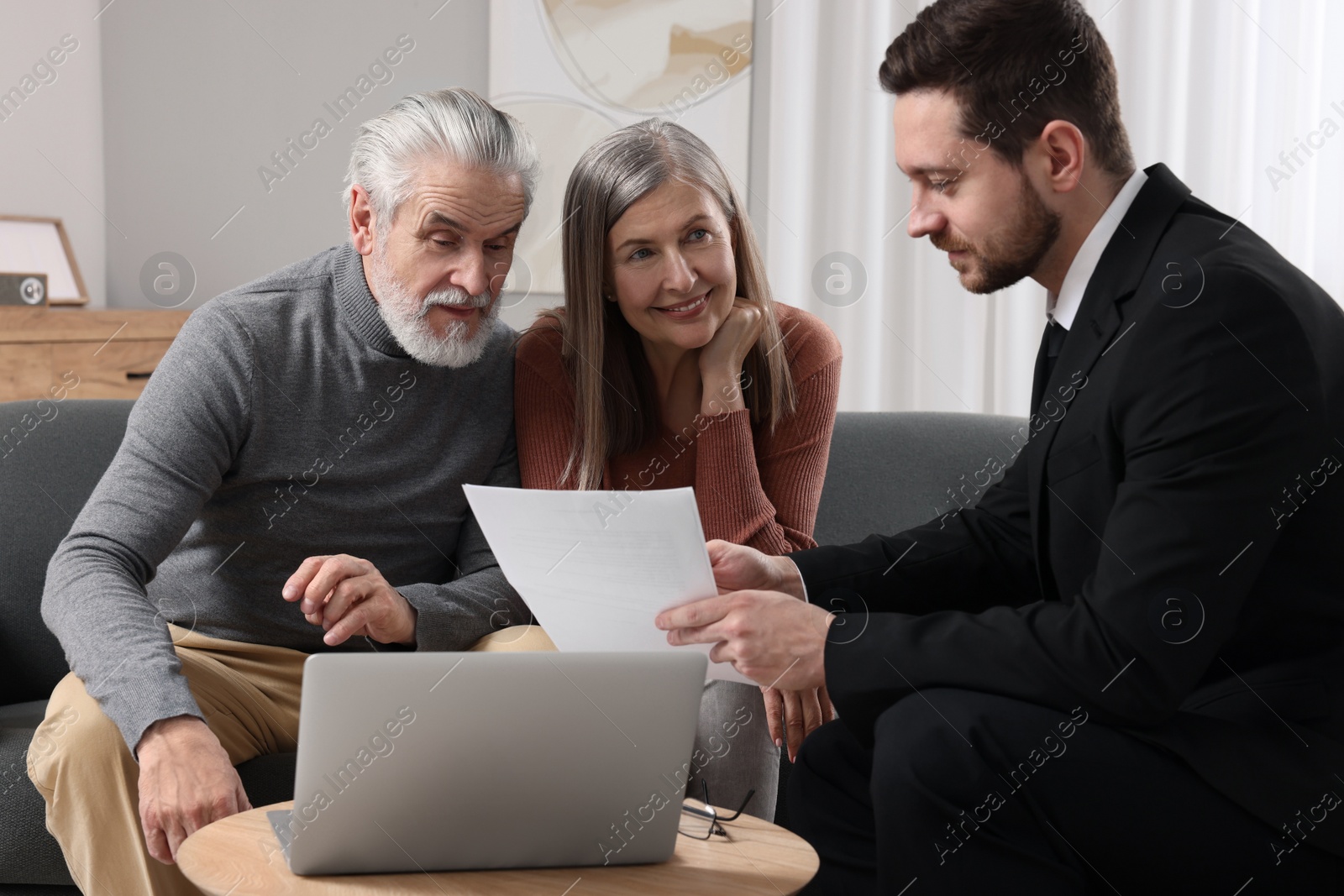 Photo of Insurance agent consulting elderly couple about pension plan in room