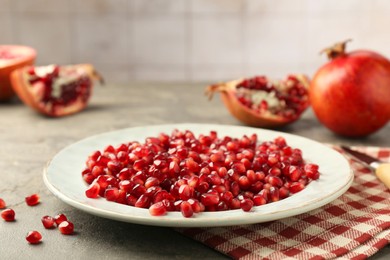 Photo of Tasty ripe pomegranate grains on grey table, closeup