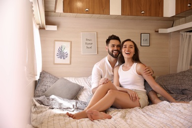 Photo of Happy young couple on bed in trailer. Camping vacation