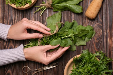 Photo of Woman with fresh green herbs at wooden table, top view