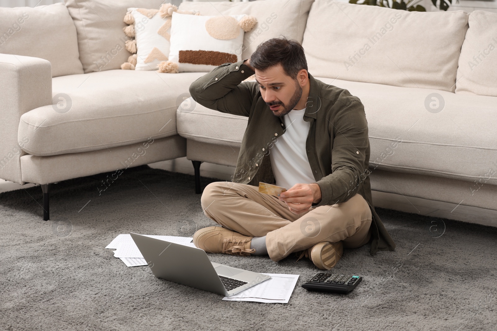 Photo of Confused man with laptop, debt notifications and credit card planning budget at home. Financial problem