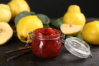 Photo of Delicious quince jam and vanilla on black wooden table, closeup