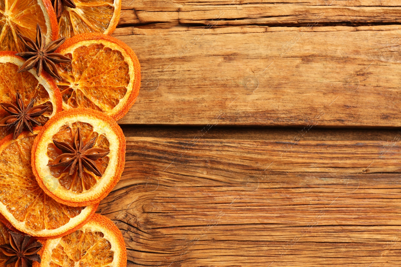 Photo of Dry orange slices and anise stars on wooden table, flat lay with space for text