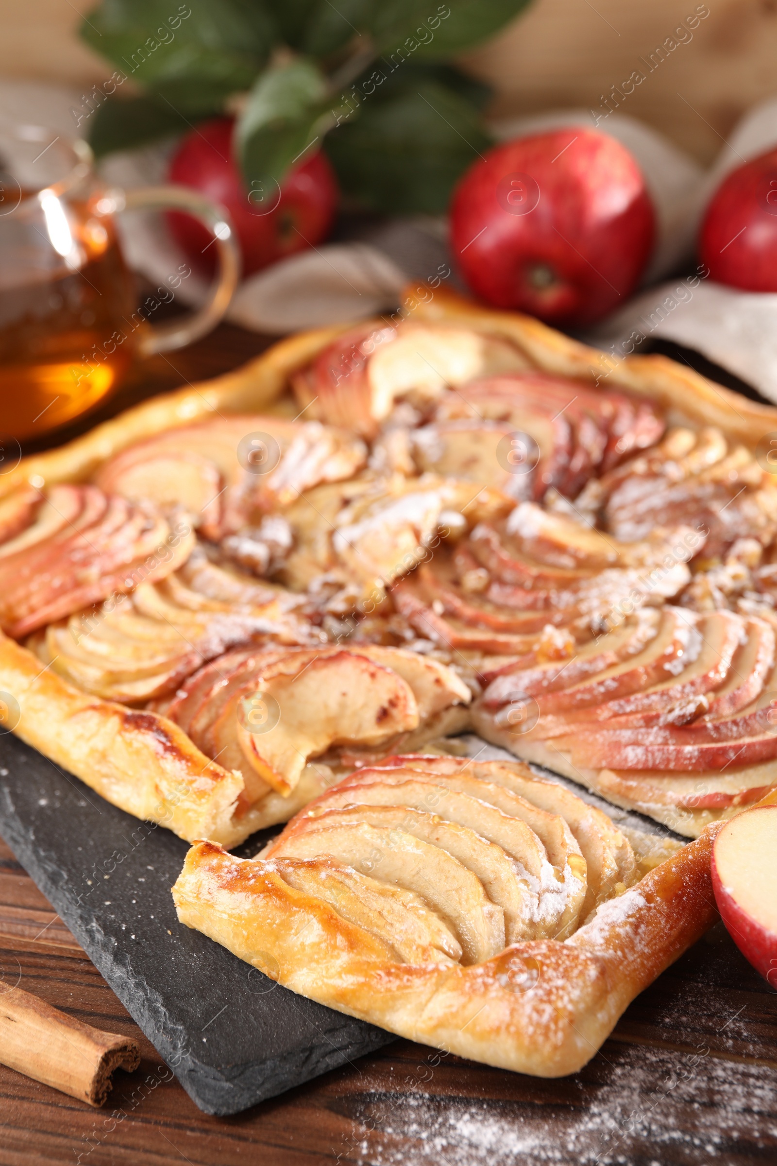 Photo of Freshly baked apple pie with powdered sugar on wooden table