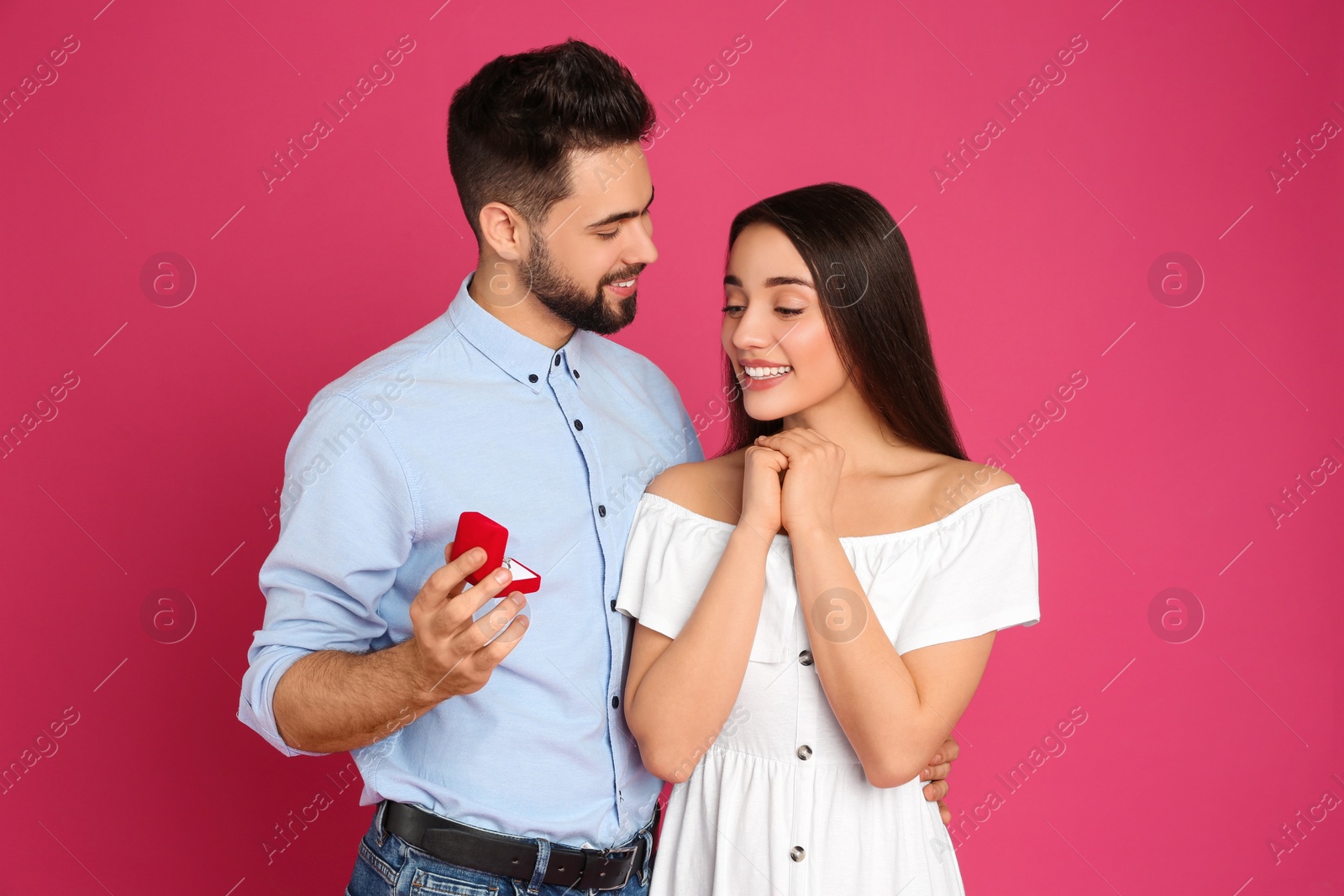 Photo of Man with engagement ring making marriage proposal to girlfriend on crimson background