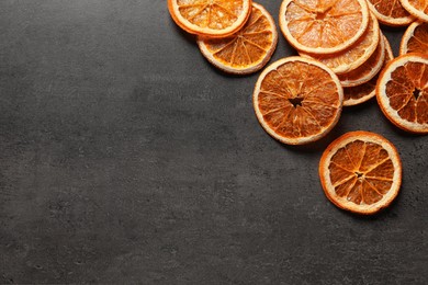 Dry orange slices on black table, flat lay. Space for text