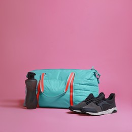 Photo of Blue gym bag and sports accessories on pink background