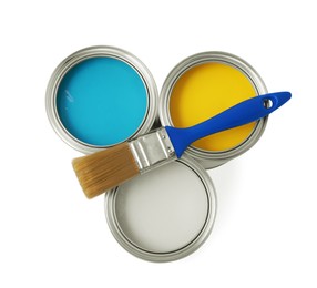 Photo of Cans with different paints and brush on white background, top view