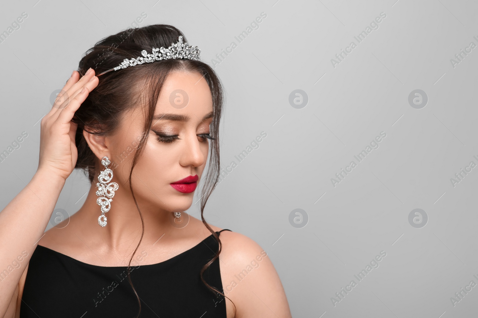 Photo of Beautiful young woman wearing luxurious tiara on light grey background, space for text