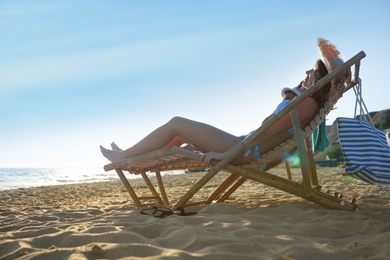 Photo of Young couple relaxing in deck chairs on beach near sea