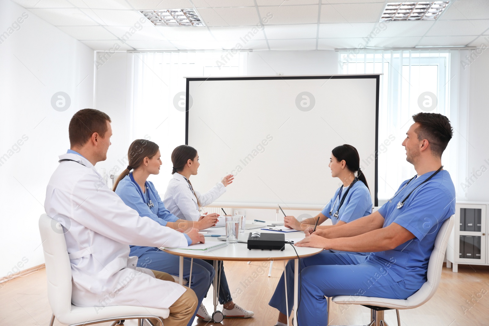 Photo of Team of doctors using video projector during conference indoors