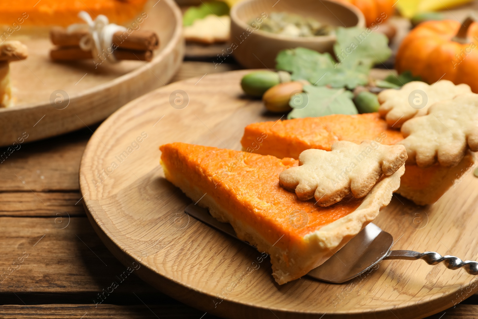 Photo of Slices of delicious homemade pumpkin pie on wooden plate, closeup