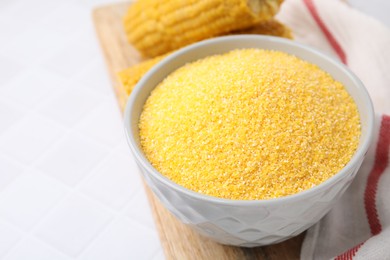 Photo of Raw cornmeal in bowl on white table, closeup. Space for text