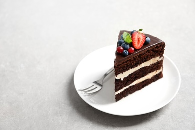 Plate with slice of chocolate sponge berry cake on grey background