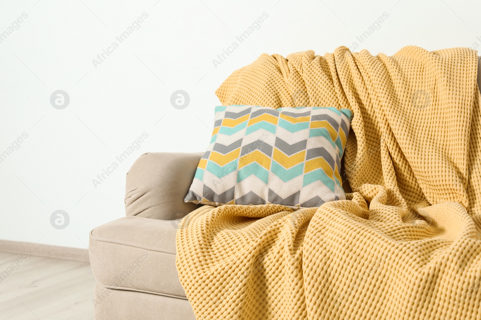 Photo of Cozy sofa with pillow and plaid near light wall. Idea for living room interior design