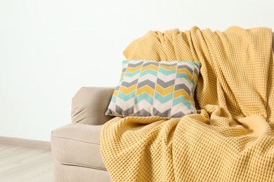 Photo of Cozy sofa with pillow and plaid near light wall. Idea for living room interior design