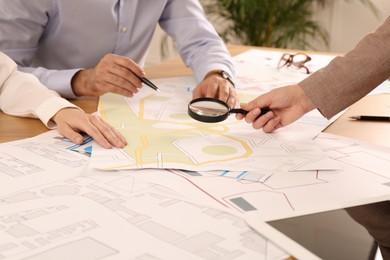 Professional cartographers working with cadastral map at table in office, closeup