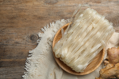 Rice noodles and ginger on wooden table, flat lay