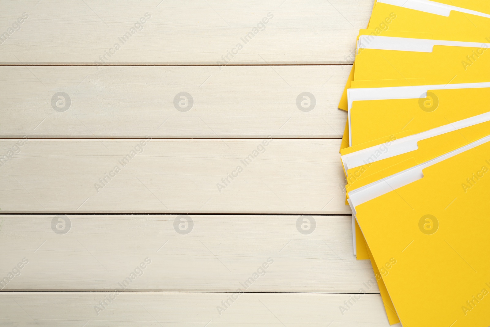 Photo of Yellow files with documents on white wooden table, top view. Space for text