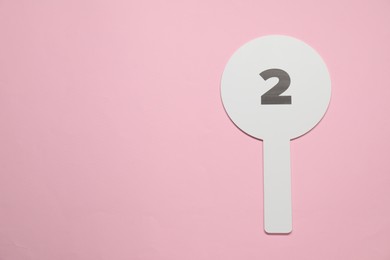 Photo of Auction paddle with number 2 on pink background, top view. Space for text